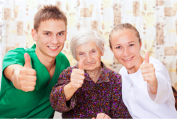 caregivers and elderly woman showing thumbs up